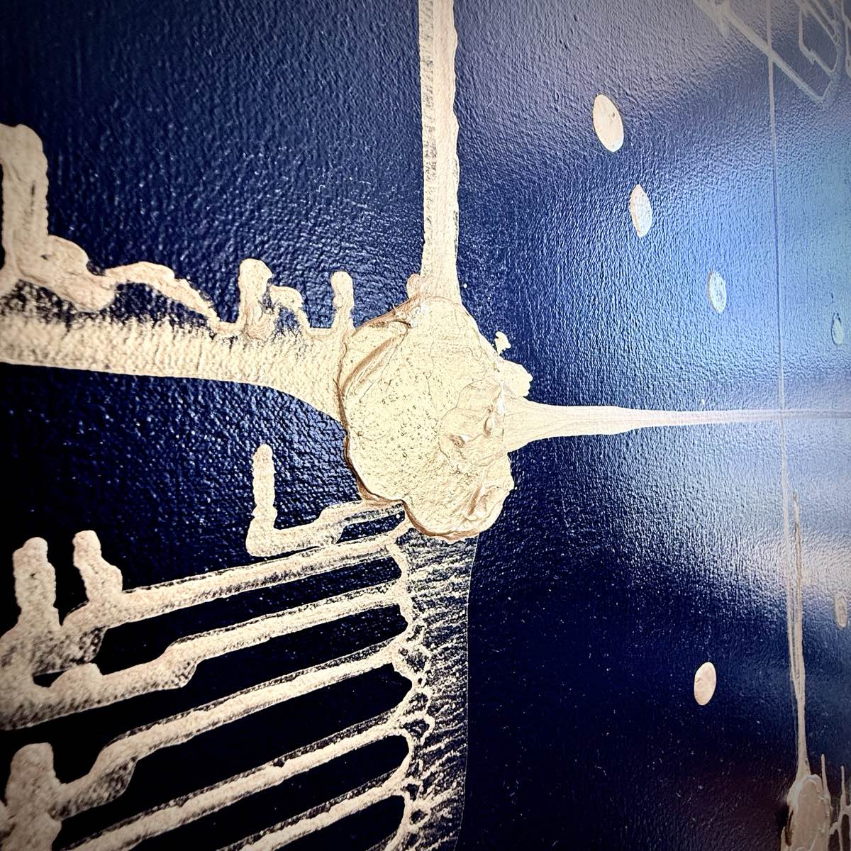 Detail of Endurance by D.C. Christian: a gold impasto node where vertical and horizontal traces cross the deep blue field, with scattered gravitationally dropped points.
